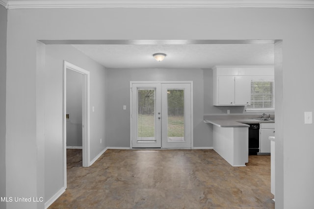 kitchen featuring white cabinets, baseboards, concrete flooring, and black dishwasher