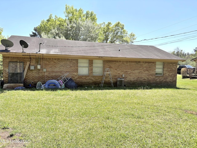 back of house featuring brick siding, central AC unit, and a lawn