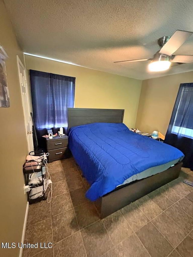 bedroom featuring a textured ceiling, baseboards, and a ceiling fan