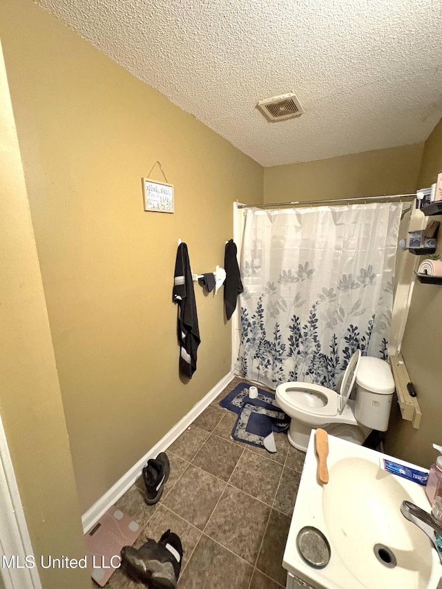 full bath featuring a shower with shower curtain, tile patterned floors, a textured ceiling, toilet, and a sink