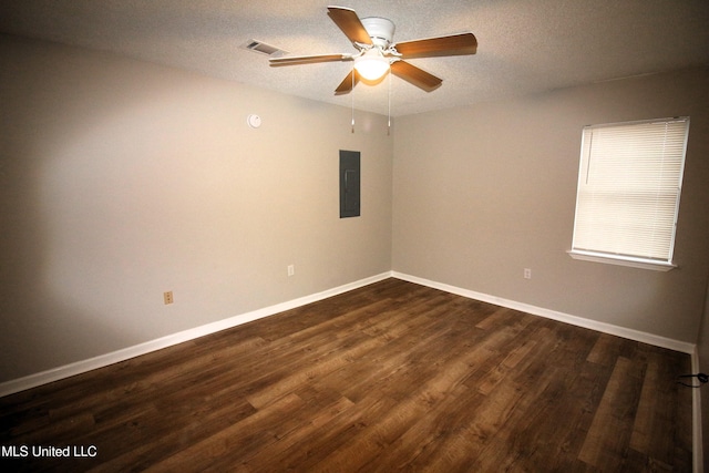 empty room with electric panel, visible vents, a textured ceiling, and dark wood finished floors