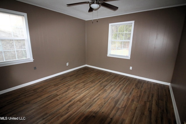 unfurnished room with baseboards, crown molding, a ceiling fan, and dark wood-style flooring