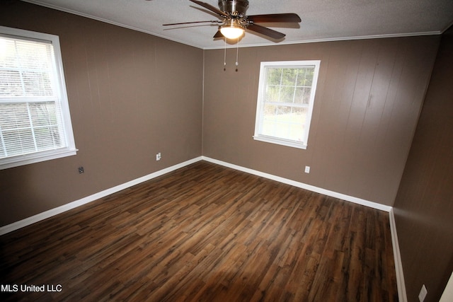 empty room with ceiling fan, baseboards, dark wood-style flooring, and crown molding