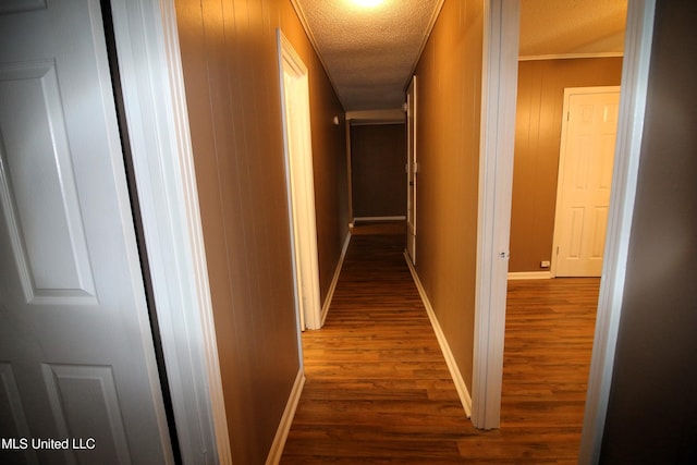 hallway featuring a textured ceiling, baseboards, and wood finished floors