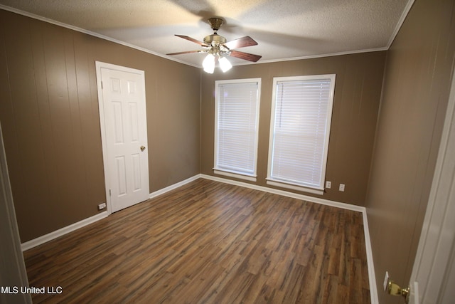 spare room with baseboards, dark wood-style flooring, ceiling fan, a textured ceiling, and crown molding