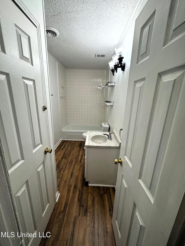 full bath featuring wood finished floors, washtub / shower combination, visible vents, a textured ceiling, and toilet