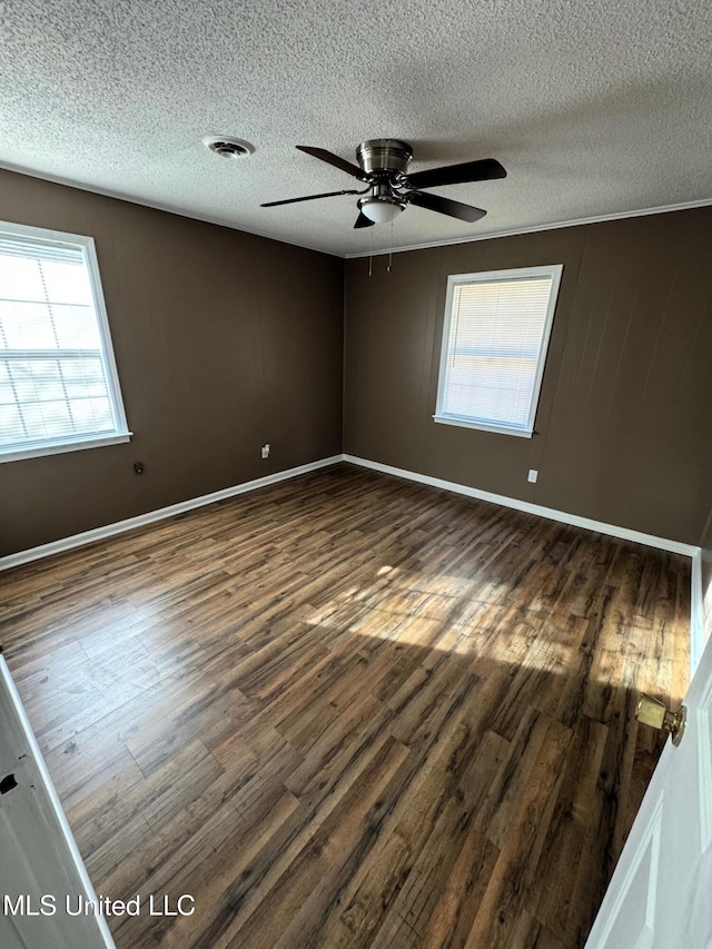 empty room with visible vents, baseboards, a ceiling fan, and dark wood-style flooring