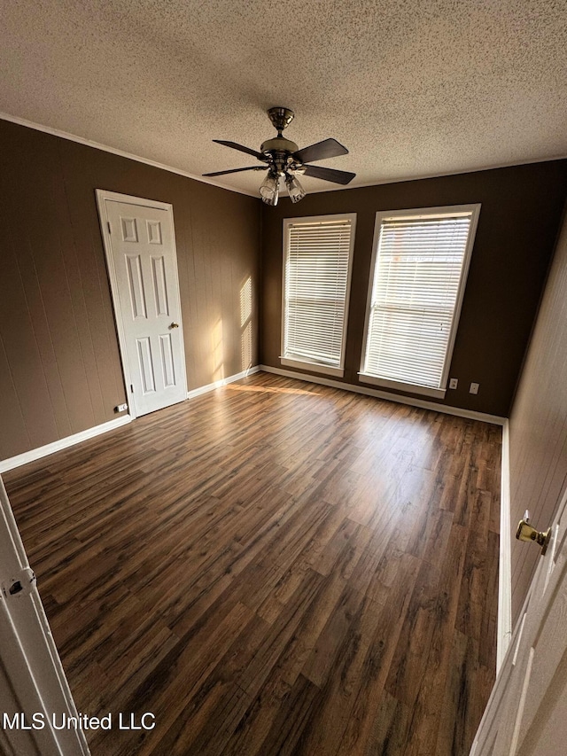 spare room with baseboards, a textured ceiling, dark wood-style floors, and a ceiling fan