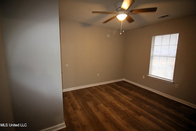 empty room with dark wood finished floors, visible vents, ceiling fan, and baseboards