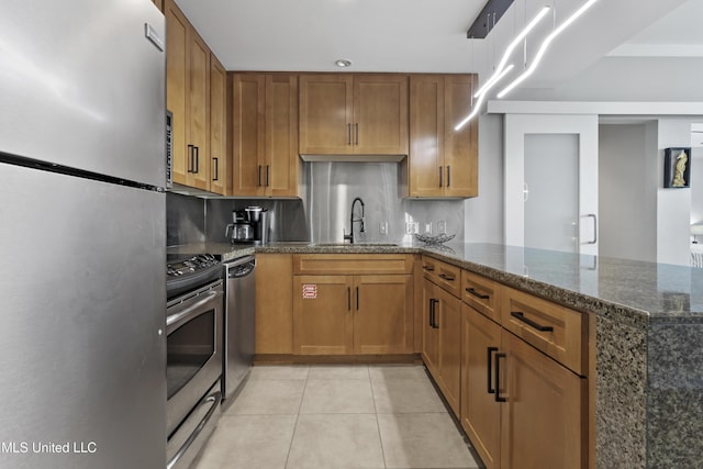 2060 Beach Blvd Unit 102, Biloxi, MS 39531 - kitchen with stainless steel appliances, light tile patterned floors, brown cabinets, and a peninsula