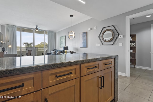 2060 Beach Blvd Unit 102, Biloxi, MS 39531 - kitchen with light tile patterned floors, ceiling fan, decorative light fixtures, dark stone counters, and brown cabinets