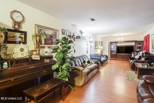 living room with a notable chandelier, hardwood / wood-style flooring, and a textured ceiling