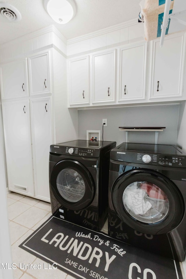 clothes washing area with cabinets, light tile patterned floors, and separate washer and dryer