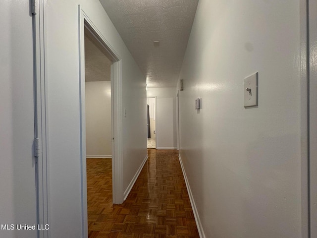 hall featuring a textured ceiling and dark parquet flooring