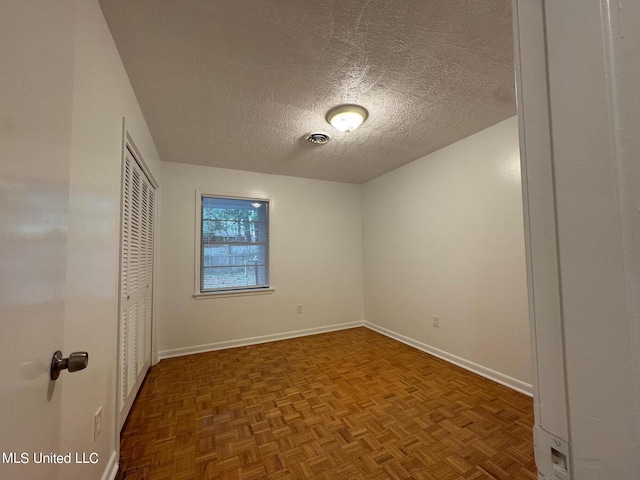 unfurnished bedroom with a textured ceiling and dark parquet floors