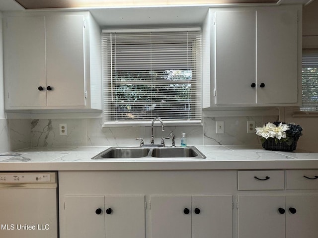 kitchen with light stone countertops, white dishwasher, sink, and white cabinets