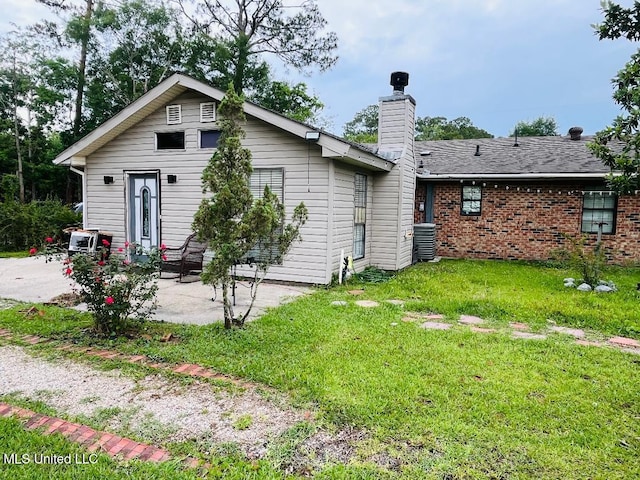 856 Saint Joseph St, Waveland, MS 39576 - rear view of house with a patio area, a yard, a chimney, brick siding, and cooling unit