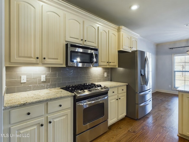 kitchen featuring light stone countertops, appliances with stainless steel finishes, dark wood-type flooring, backsplash, and ornamental molding