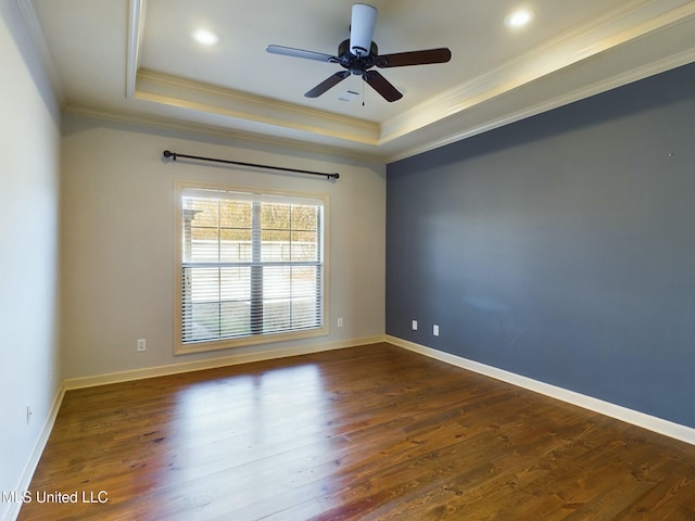 spare room featuring ceiling fan, a tray ceiling, dark hardwood / wood-style floors, and crown molding