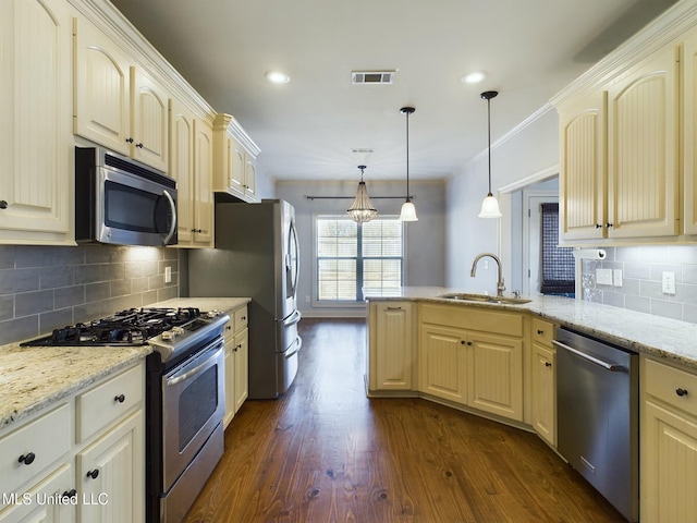 kitchen with light stone countertops, decorative light fixtures, dark hardwood / wood-style flooring, stainless steel appliances, and sink