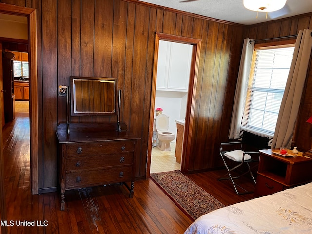 bedroom with crown molding, wooden walls, sink, dark hardwood / wood-style floors, and connected bathroom