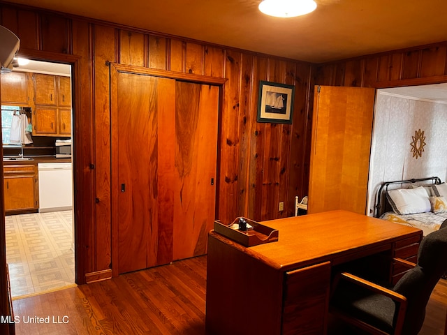 home office with hardwood / wood-style flooring, sink, and wooden walls