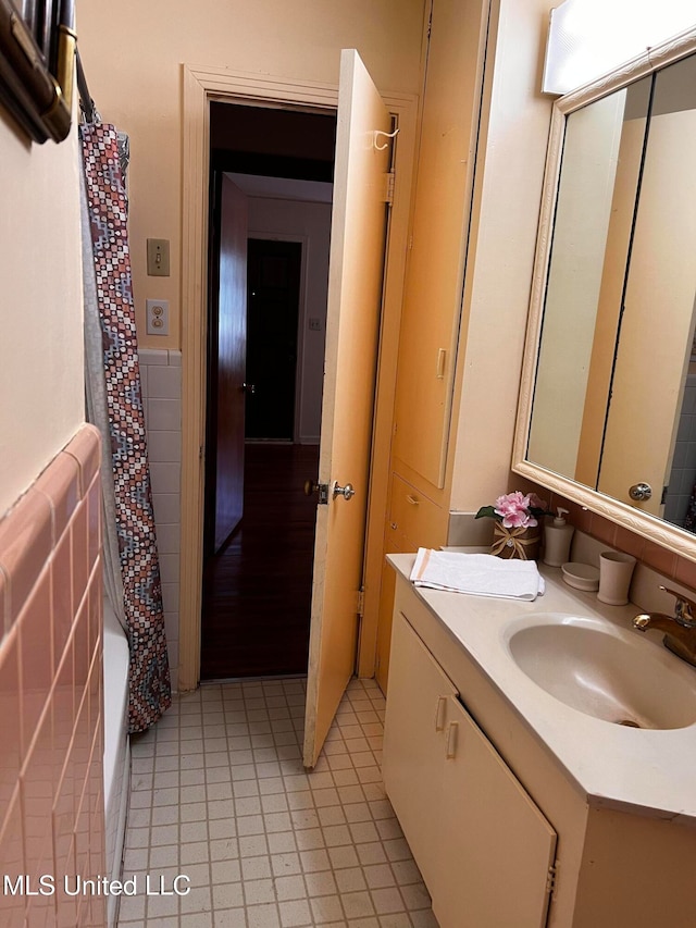 bathroom with tile patterned floors, vanity, shower / bathtub combination with curtain, and tile walls