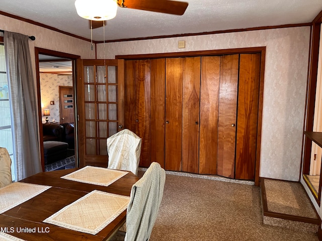 carpeted dining room featuring ceiling fan, a textured ceiling, and ornamental molding