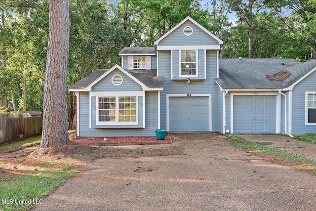 traditional-style house with a garage, fence, a shingled roof, and aphalt driveway