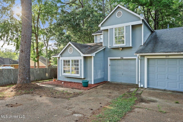 traditional-style house with a shingled roof, fence, and driveway