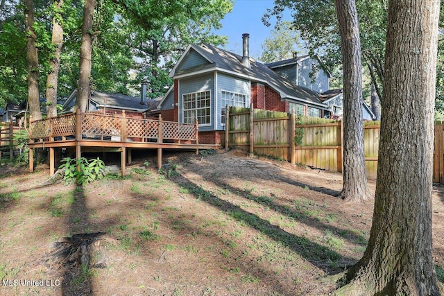 rear view of property featuring fence, a wooden deck, and brick siding