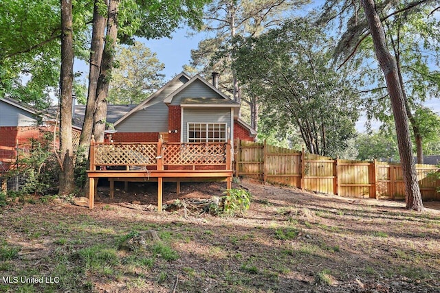 rear view of property with brick siding, a deck, and fence