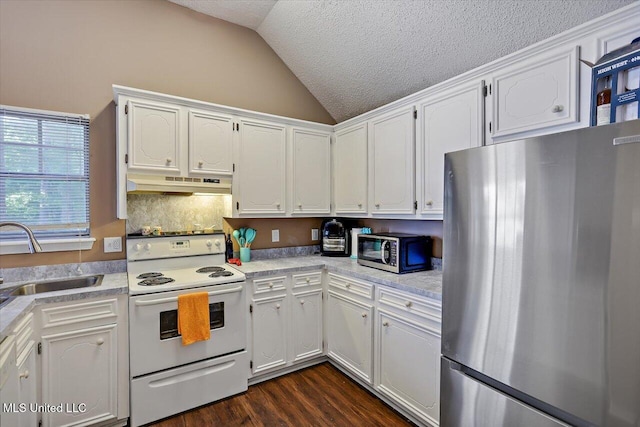 kitchen with appliances with stainless steel finishes, vaulted ceiling, a sink, under cabinet range hood, and white cabinetry