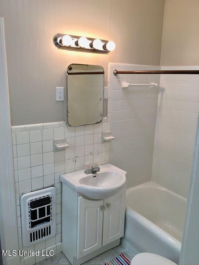 full bathroom featuring tile walls, vanity, and toilet