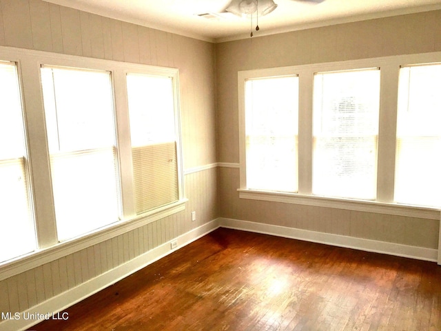 empty room with ceiling fan, crown molding, a wealth of natural light, and dark hardwood / wood-style flooring