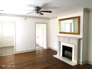 unfurnished living room with crown molding, a healthy amount of sunlight, dark wood-type flooring, and ceiling fan