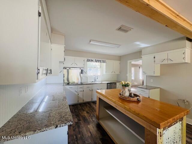 kitchen with white cabinetry, light stone countertops, dark wood-type flooring, and stainless steel dishwasher