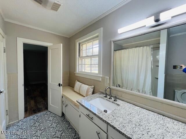 bathroom featuring a textured ceiling, tile patterned floors, tile walls, vanity, and crown molding