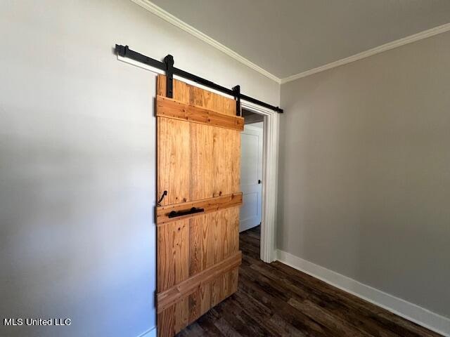 interior space with ornamental molding, a barn door, and dark hardwood / wood-style flooring