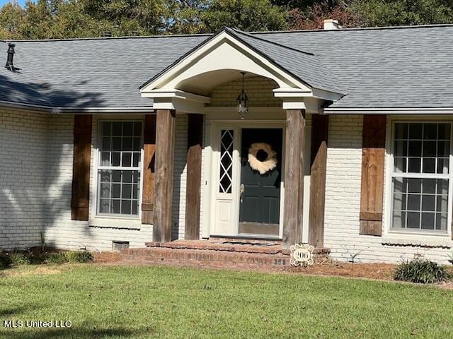 entrance to property featuring a lawn and a porch