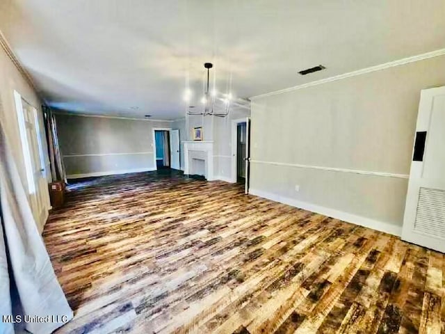 unfurnished living room featuring wood-type flooring, ornamental molding, and an inviting chandelier