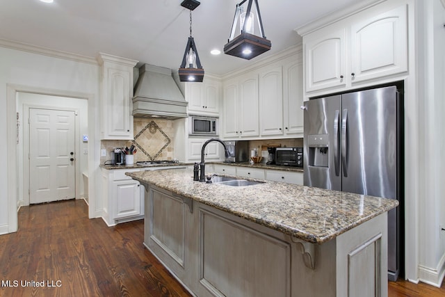 kitchen with custom exhaust hood, white cabinetry, a kitchen island with sink, light stone countertops, and sink