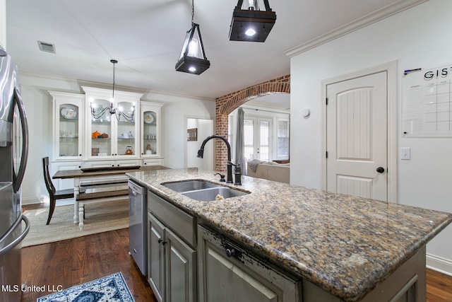 kitchen with a kitchen island with sink, dark stone counters, sink, gray cabinets, and dark hardwood / wood-style flooring