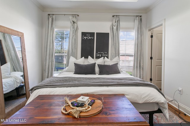 bedroom featuring hardwood / wood-style flooring, ornamental molding, and multiple windows