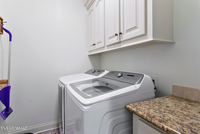 clothes washing area with cabinets and separate washer and dryer