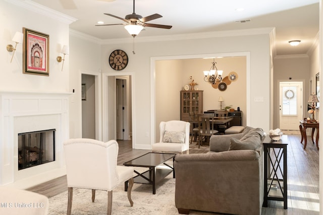 living area with a glass covered fireplace, visible vents, crown molding, and wood finished floors