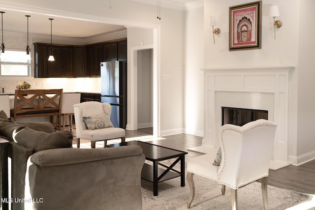 living area featuring baseboards, a fireplace, ornamental molding, and wood finished floors