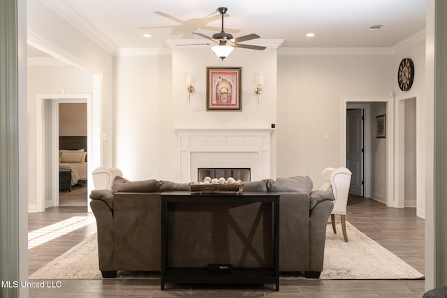 living area with ornamental molding, a fireplace, wood finished floors, and visible vents