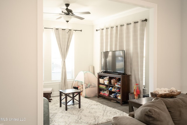 living area featuring a ceiling fan, crown molding, and wood finished floors