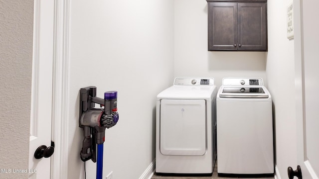 laundry room featuring cabinet space, baseboards, and separate washer and dryer